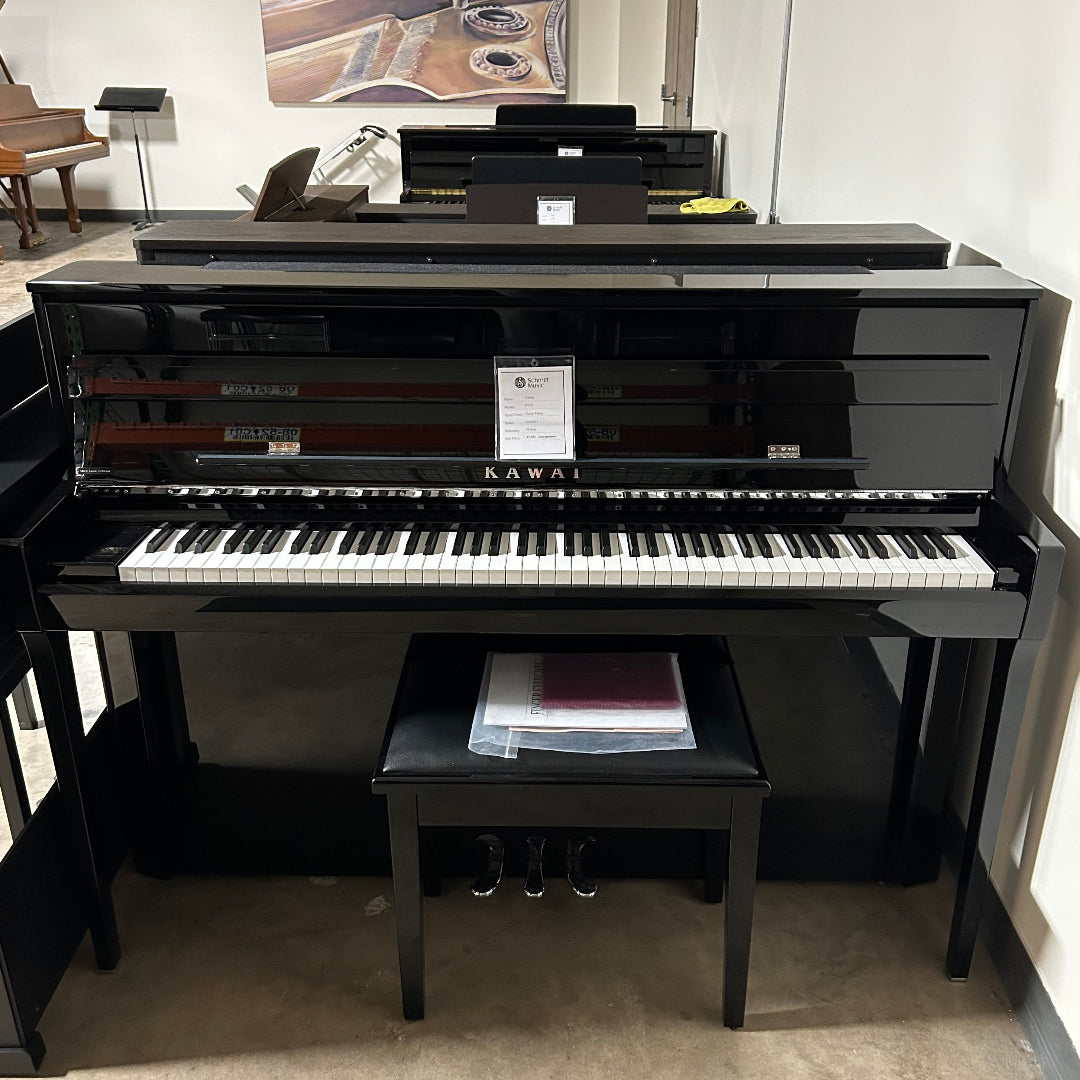 A glossy black upright piano with a matching bench in a showroom or indoor room setting.