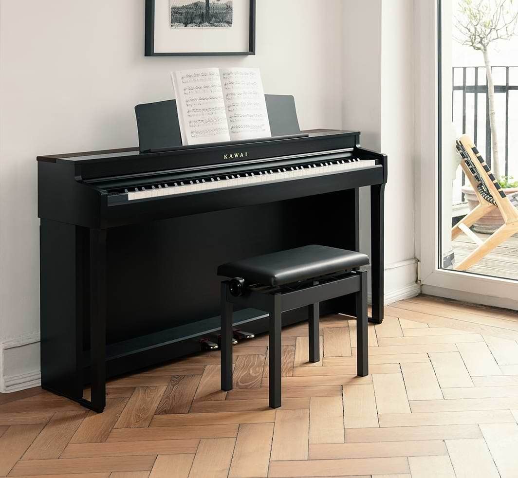 Black Kawai digital piano with bench in a room with a window and plant