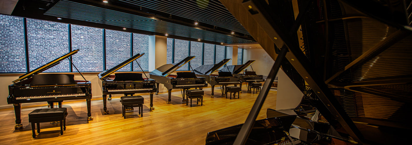 A row of grand pianos in a showroom settting