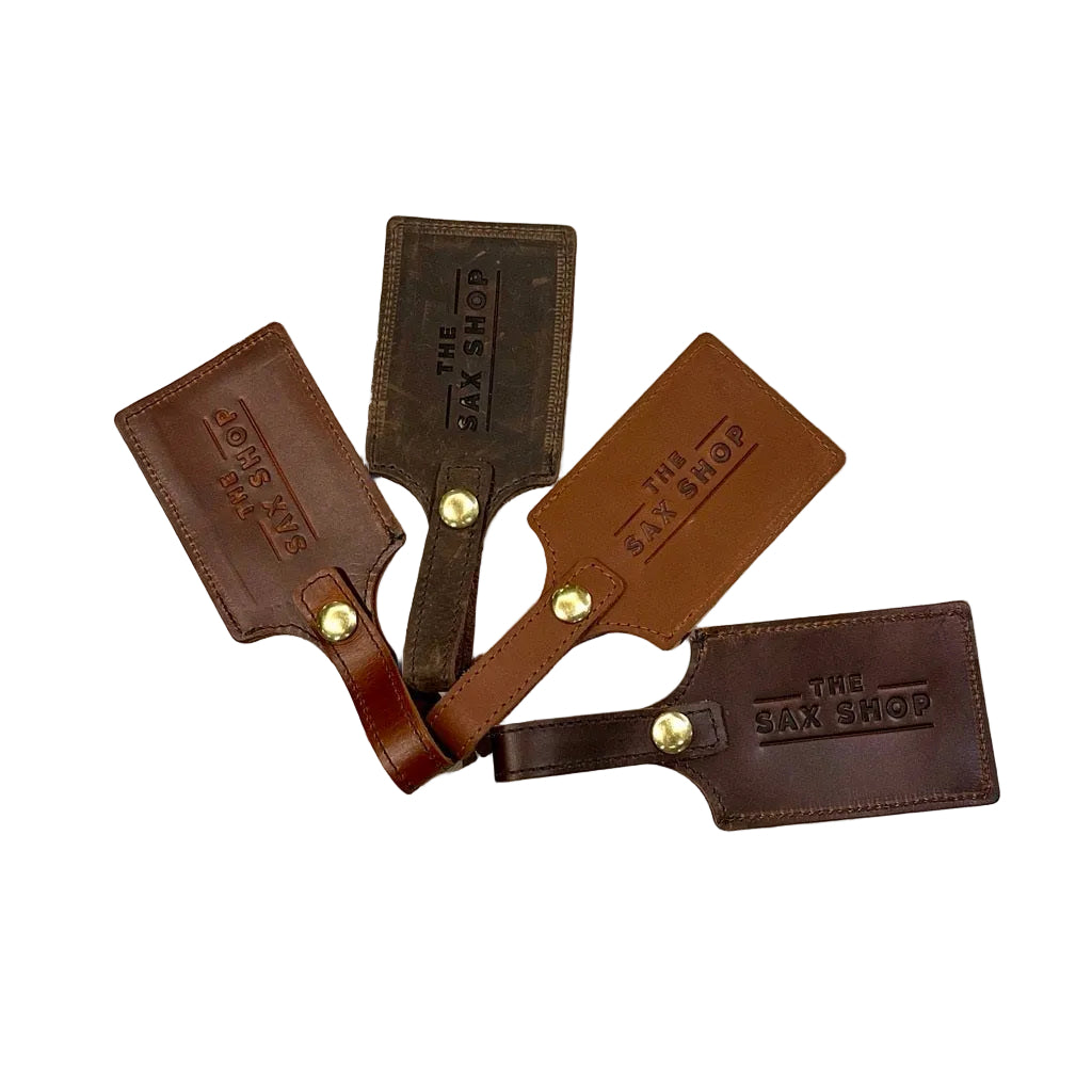 Four leather luggage tags that have "Sax Shop" imprinted on them. They are different colors.