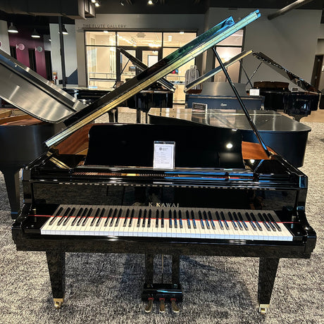 A black Yamaha grand piano with its lid open, positioned in a showroom with other pianos and musical instruments in the background.