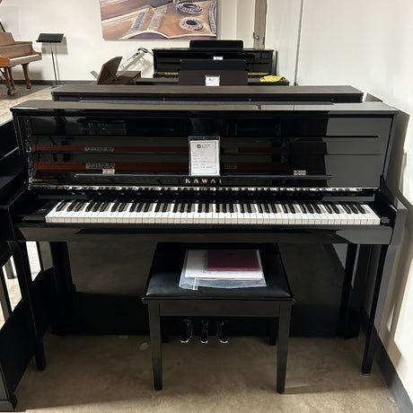 A glossy black upright piano with a matching bench in a showroom or indoor room setting.