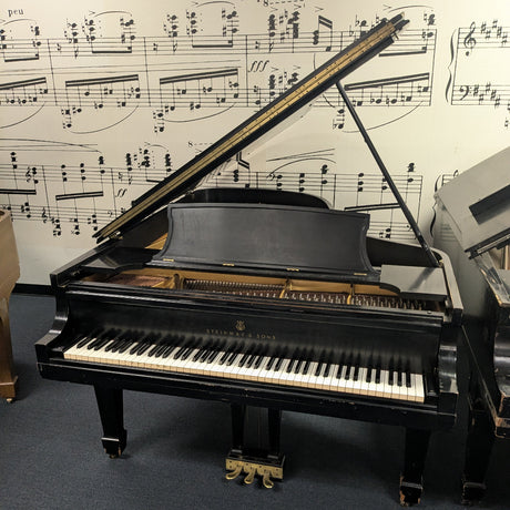 Grand piano in a room with sheet music on the wall