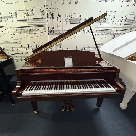 Two grand pianos, one brown and one white, against a background of sheet music.