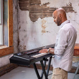 Man playing a Kawai Digital keyboard in a room with peeling paint on the walls