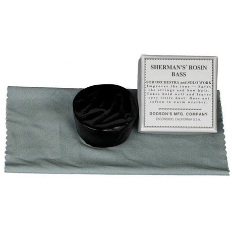 The Sherman Bass Rosin sitting on its silk cloth, that is folded underneath, and it is next to the cardboard package.